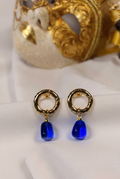 Blauwe Murano glas oorbellen met Venetiaans masker op de achtergrond